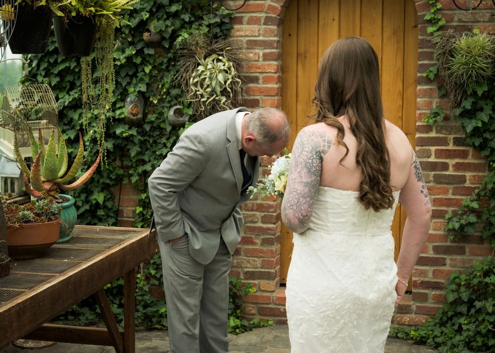 Emotional father seeing his tattooed bride daughter for the first time on their wedding day outdoors.