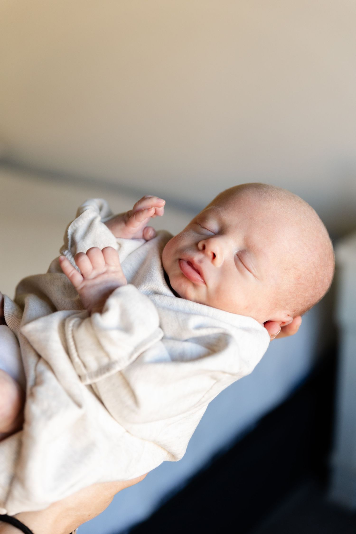 baby in moms outstretched arms in oversized sweater st. George photographer in newborn heaven