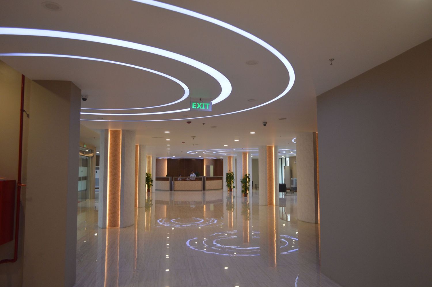 Modern office hallway with curved LED lighting fixtures creating concentric circles on the ceiling.