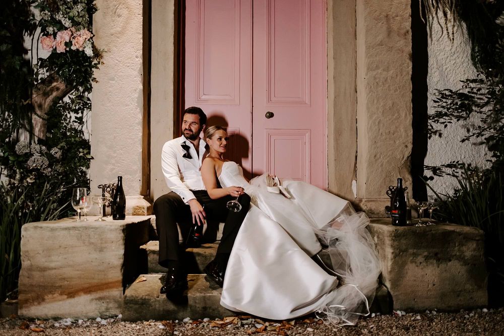 Romantic wedding couple embraces in a series of intimate poses against a rustic stone wall with a pink door.