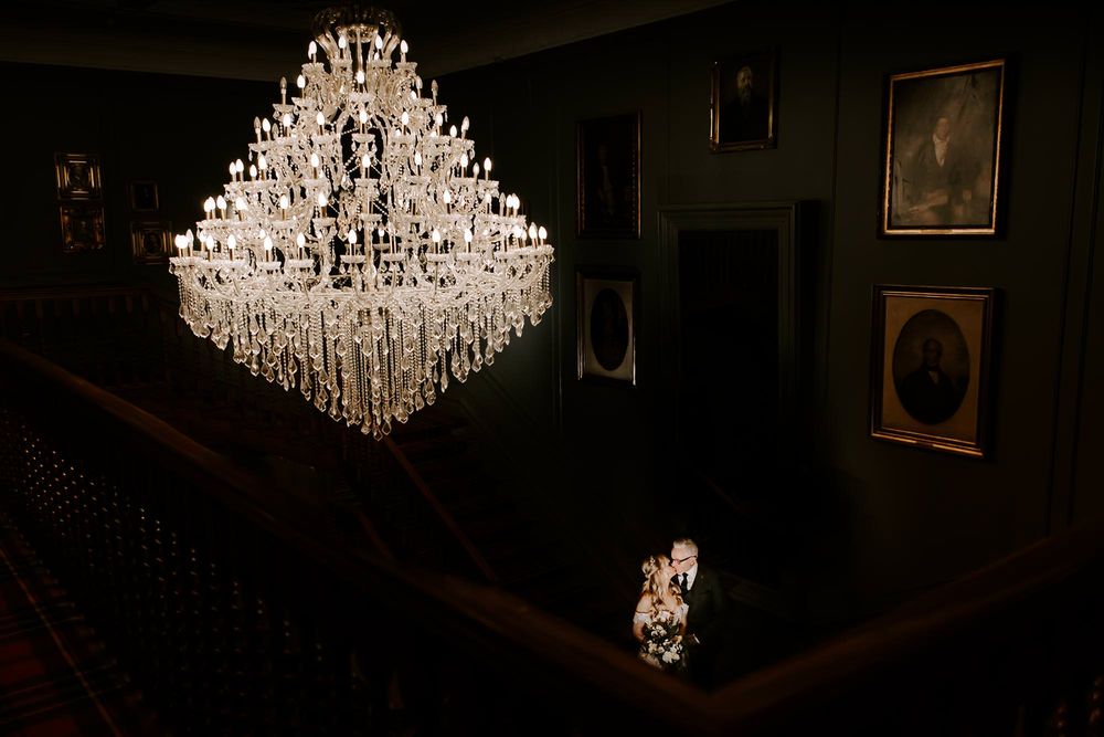 Crystal chandeliers illuminate a dark elegant room creating a glamorous atmosphere.