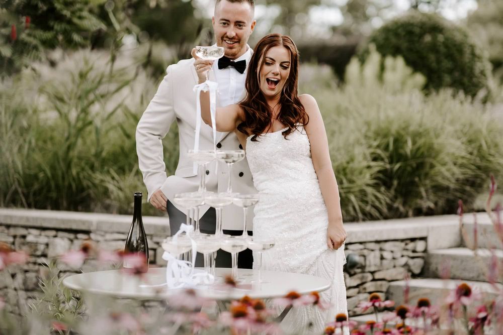 Elegant outdoor wedding reception setup with floral arrangements and white decor in a garden setting.