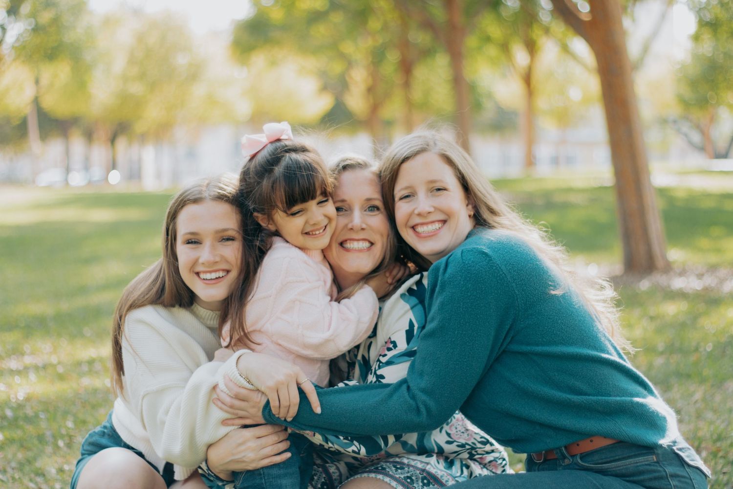 Group of friends sharing warm embraces and joyful moments together outdoors in a park setting.