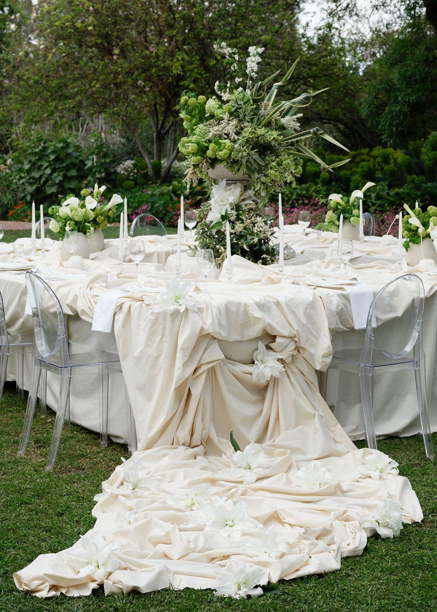Elegant outdoor wedding reception table with flowing cream tablecloth and tall floral centerpieces in a garden setting at Al Ru Farm