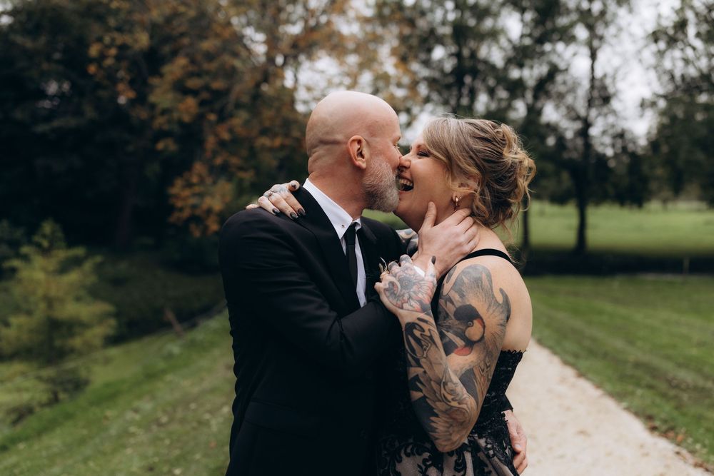 A romantic couple shares an intimate kiss outdoors during golden hour in a park setting.