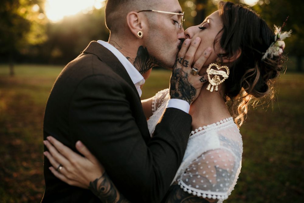 A romantic couple embraces during golden hour sunset in a garden setting wearing formal wedding attire.