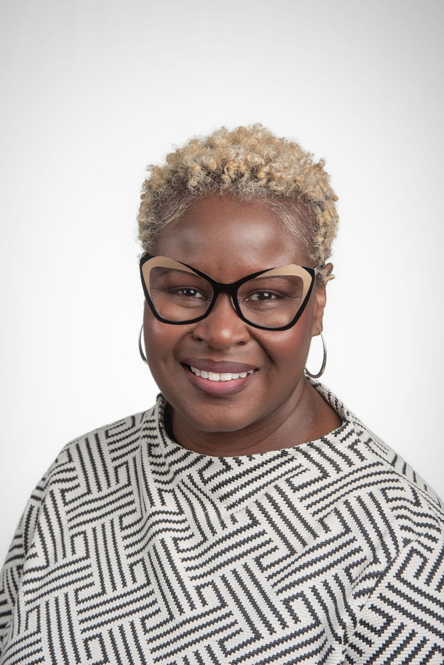 Professional business headshot of woman with blonde hair and glasses on white background.