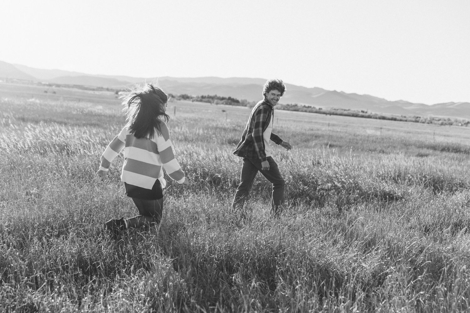 A sequence of black and white photos shows people running and playing in a grassy field on a sunny day.