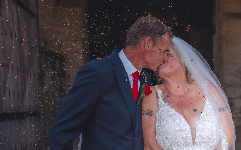 A wedding couple shares intimate kisses in a series of romantic photos against a rustic brick backdrop.