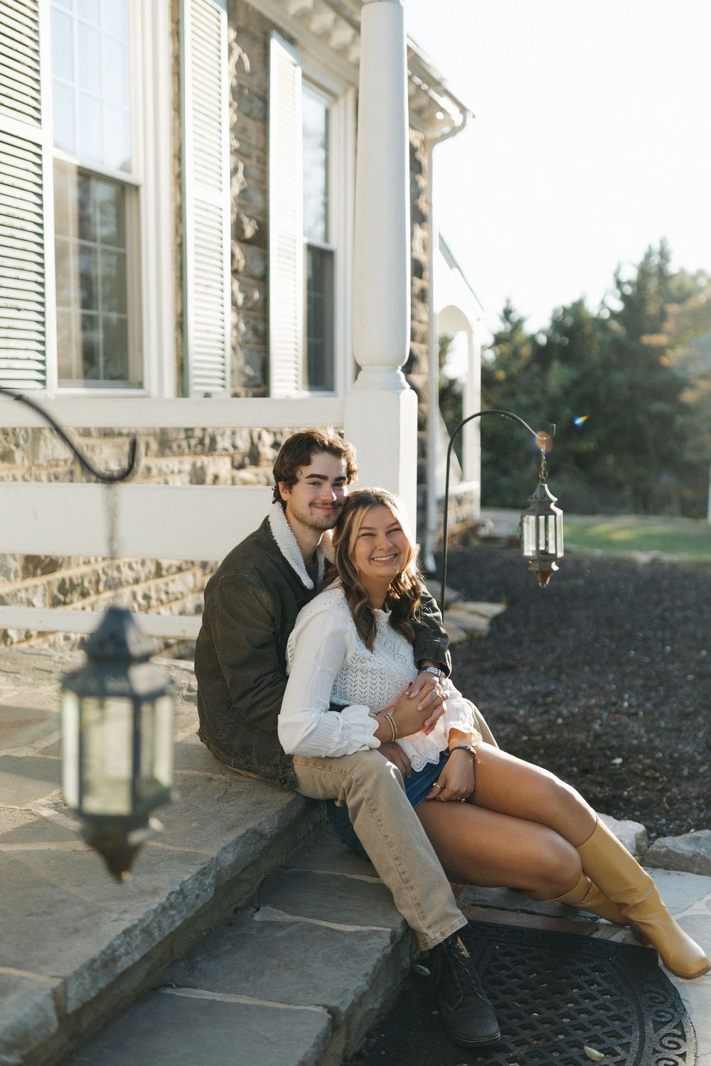A romantic couple sits together on outdoor steps during a golden hour photoshoot.