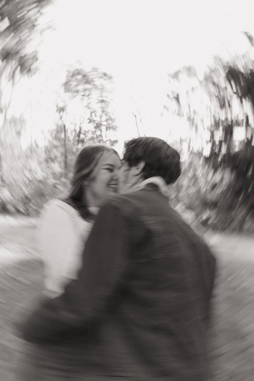 A romantic black and white photo sequence showing a couple sharing a tender kiss in a park setting.