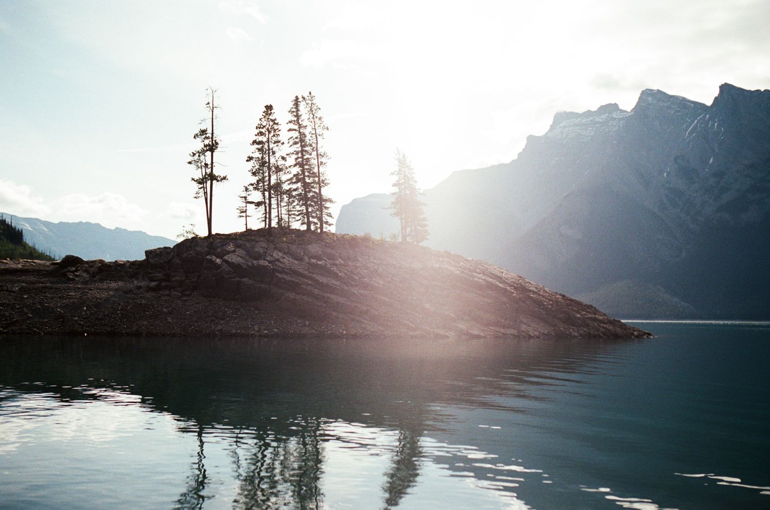 35 mm film photo of the rocky shoreline of a mountain lake in Kananaskis at sunrise