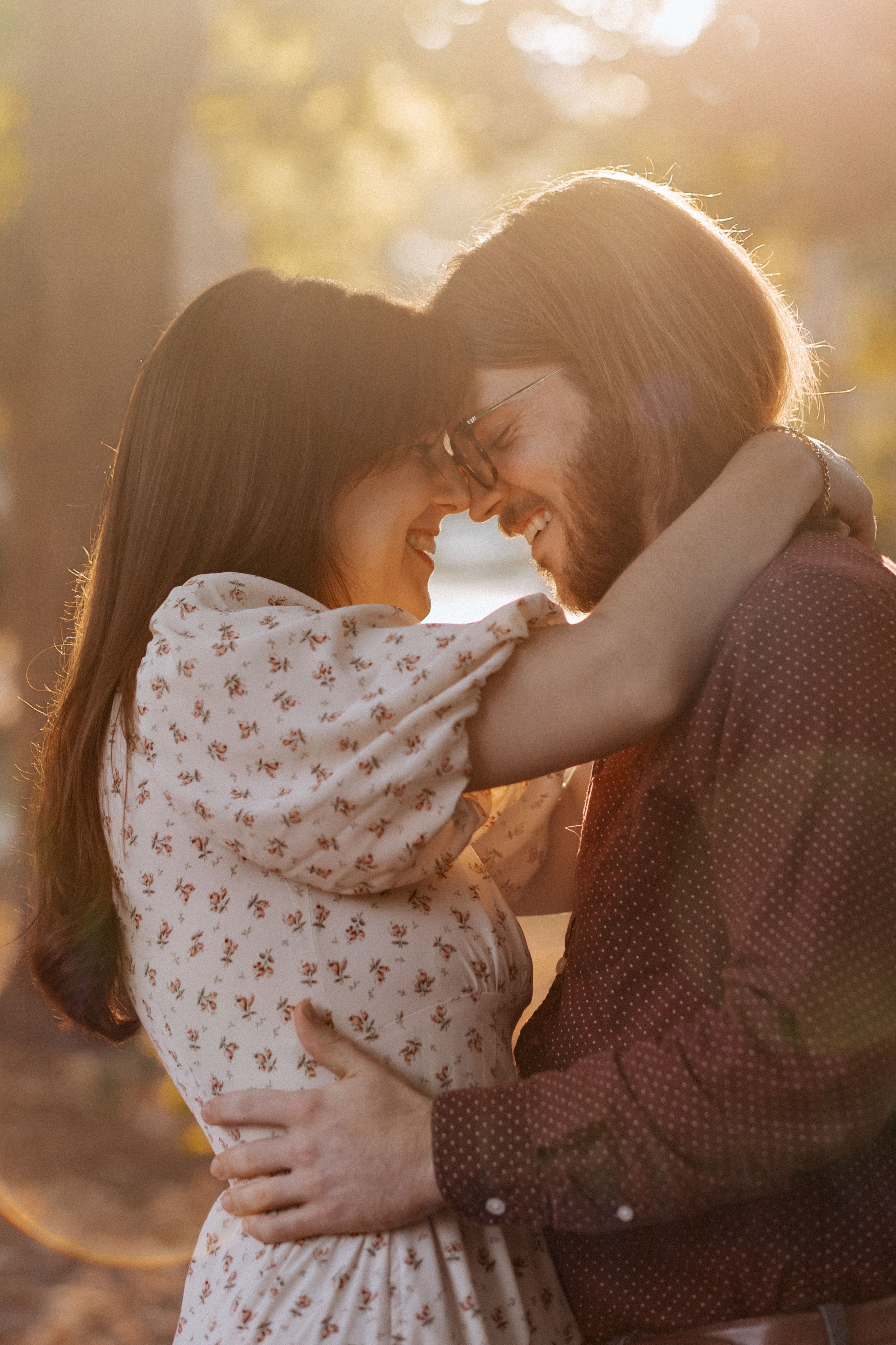 A romantic couple embraces in warm sunset light while sharing an intimate moment outdoors.