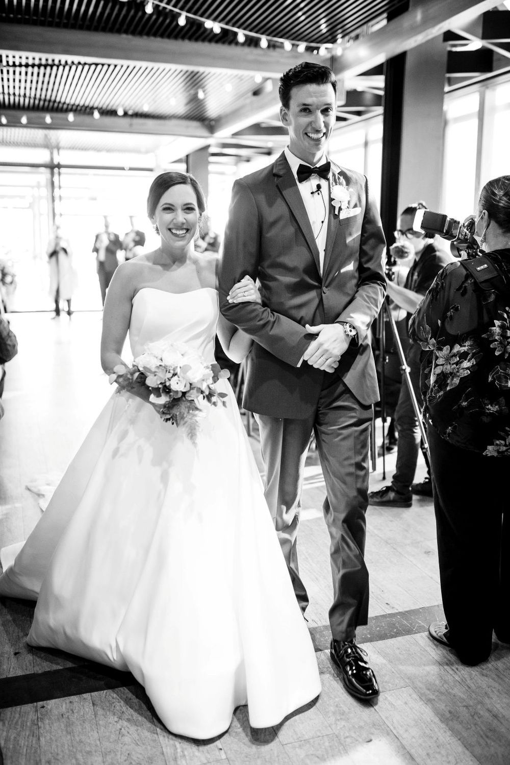 A bride and groom share a joyful dance together at their wedding reception on a polished wooden floor.