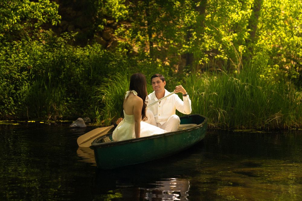 Couple enjoying romantic canoe ride through lush green waters at sunset.