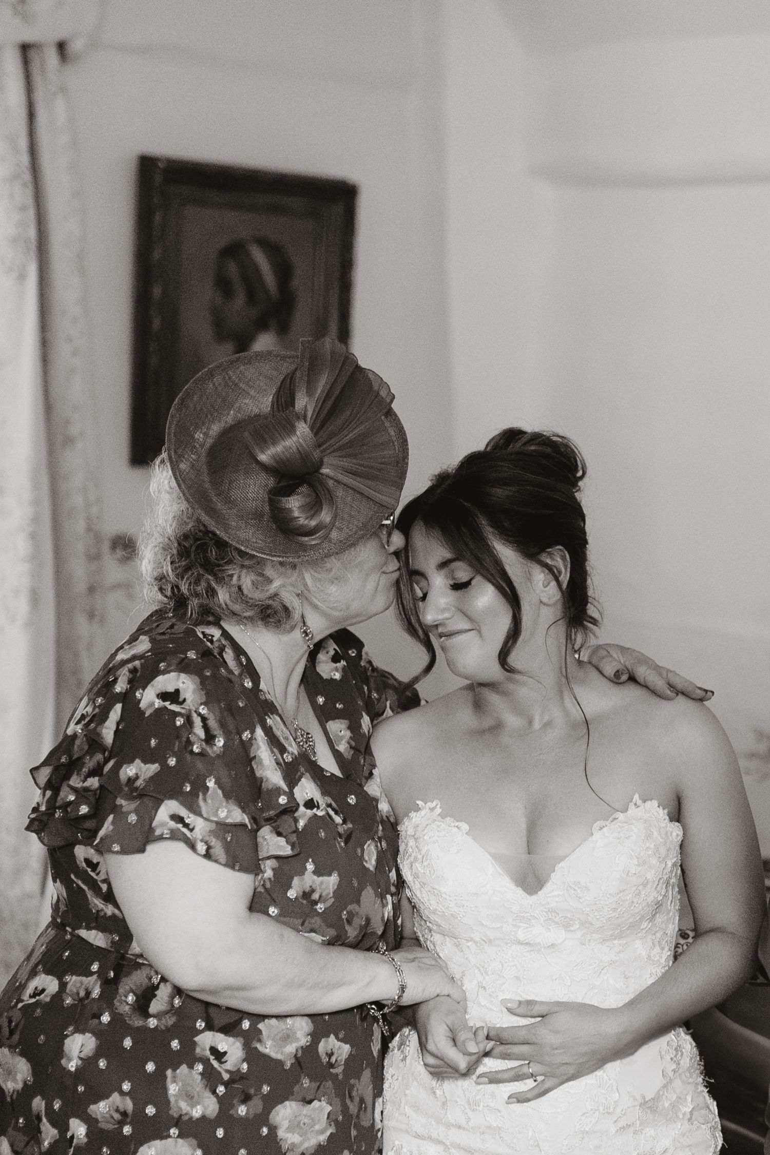 Bride and mum in floral print and wedding dress embrace during what appears to be a wedding preparation moment wedding at Lyde Court, Herefo