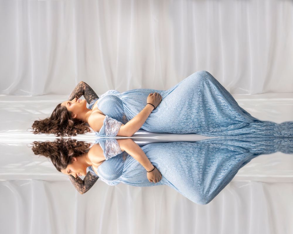 A person wearing light blue loungewear lies comfortably on a white couch in various relaxed positions.
