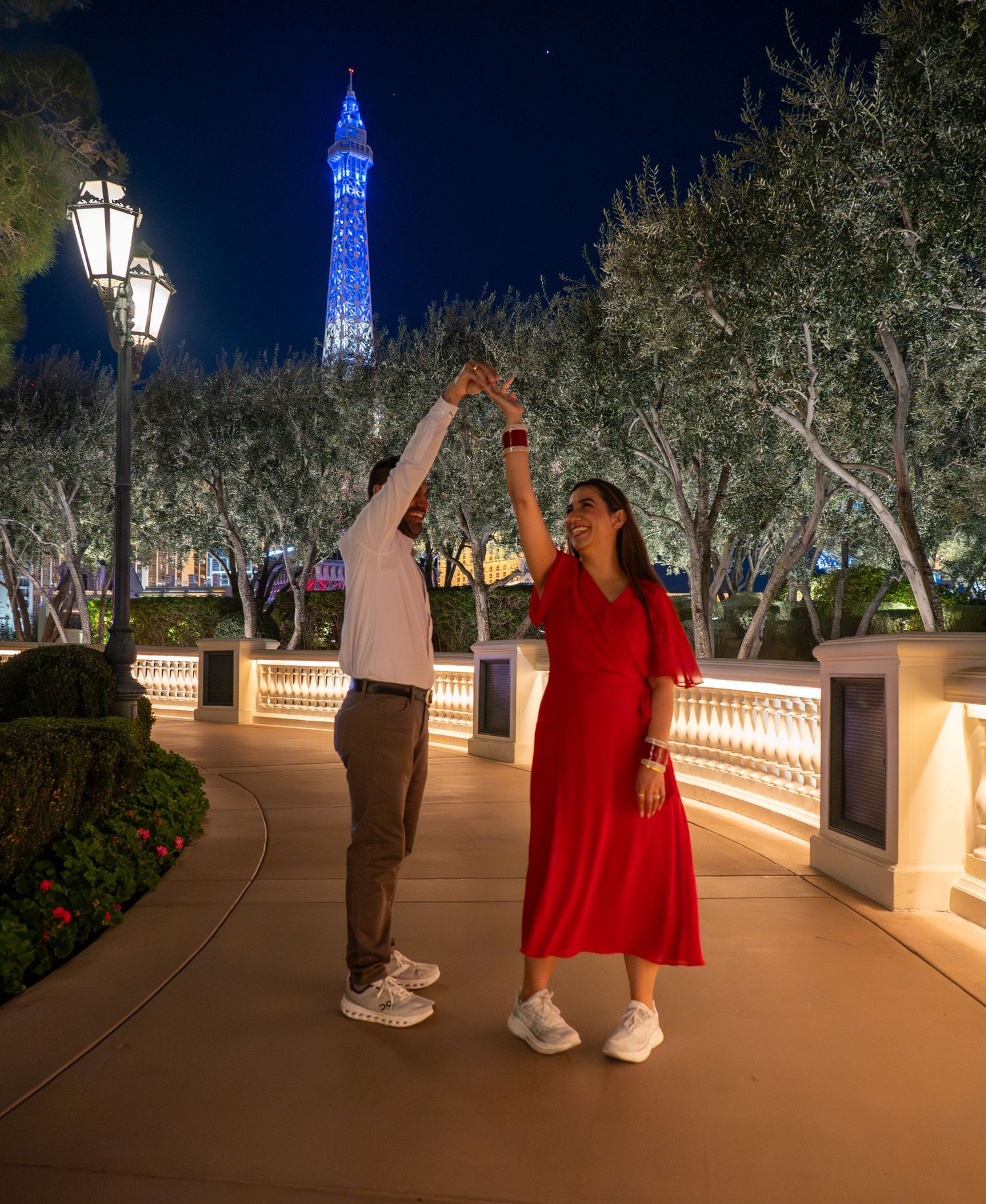 Couple dancing under Paris Las Vegas Eiffel Tower lights on romantic evening promenade.