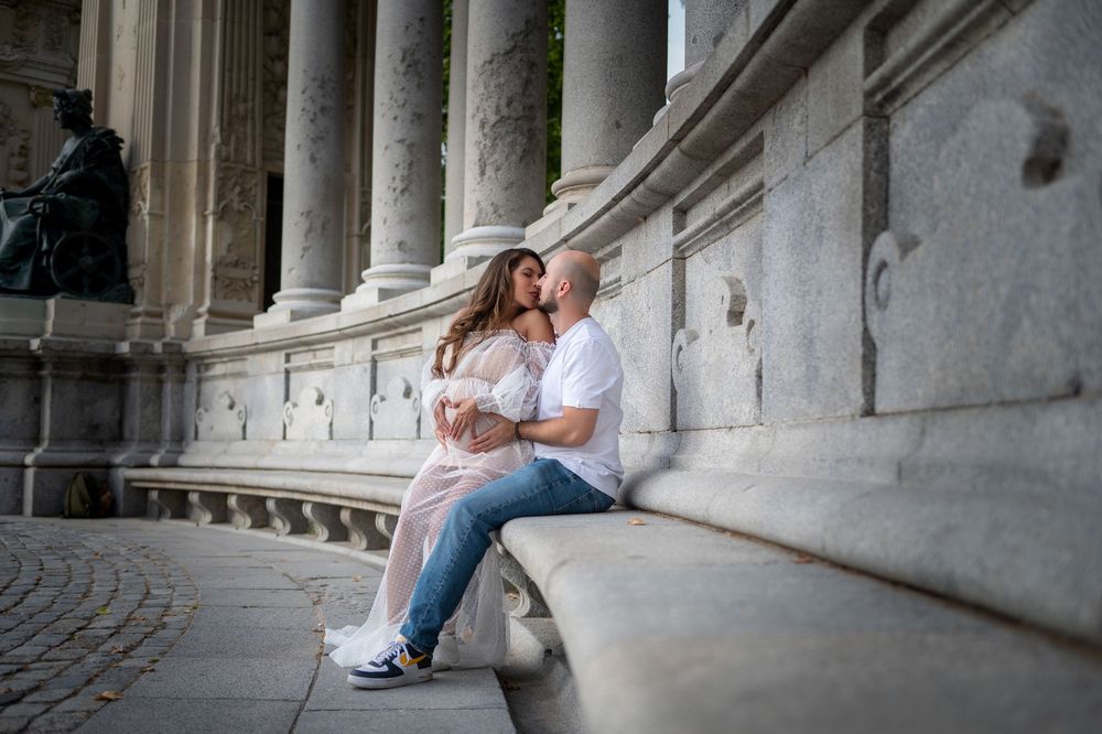 Couple sitting together on stone steps of a classical colonnade in romantic engagement photo series.