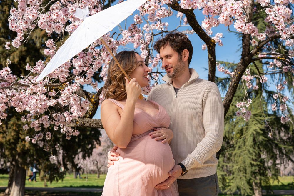 A couple embraces under blooming cherry blossom trees in a romantic spring photoshoot.