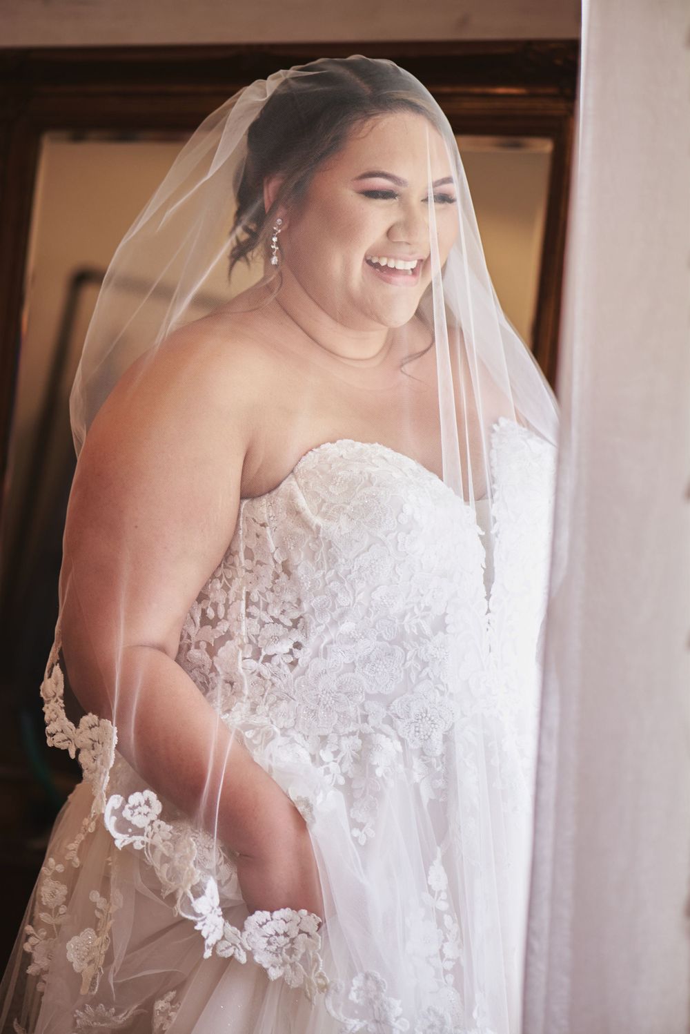 Delicate lace details and embroidery adorn a white wedding gown with a flowing veil.