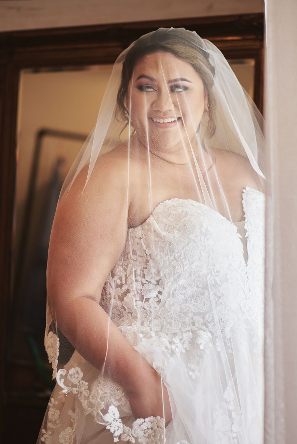 A close-up view of intricate lace details on a white wedding dress with a flowing veil.