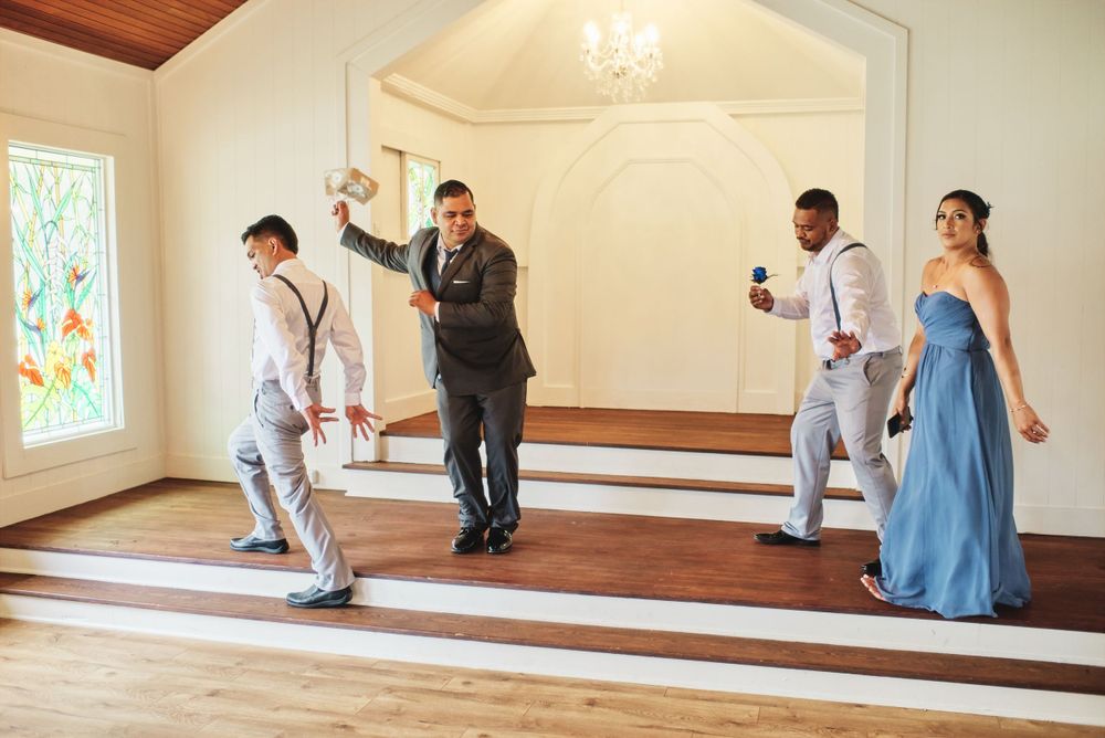 People in formal attire gather in a bright indoor space with wooden floors and white walls.