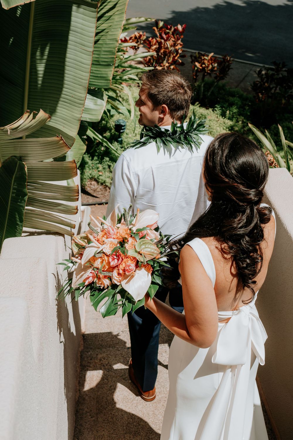 Romantic outdoor wedding portraits with lush greenery and coral-colored flowers.