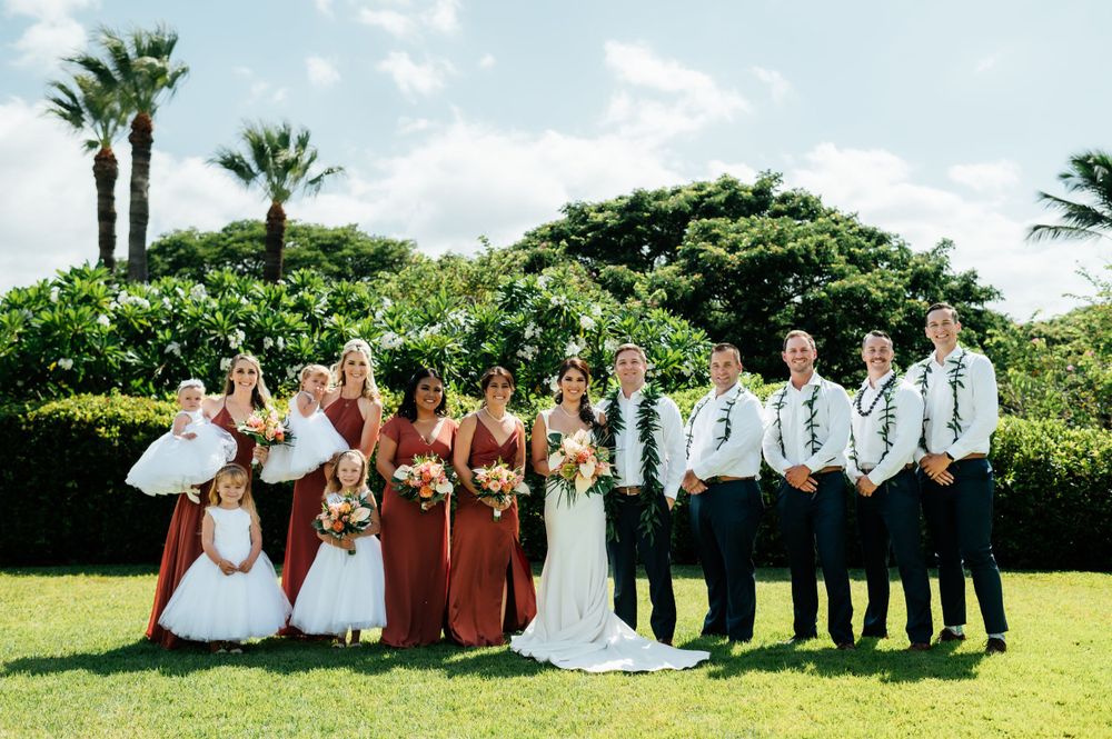 Panoramic wedding party photo with bridesmaids and groomsmen on tropical grounds.
