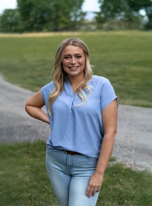 Casual summer fashion shoot on dirt path wearing light blue top and jeans.