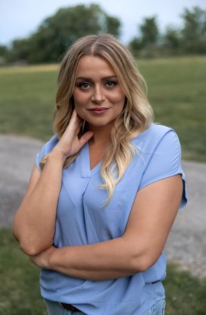 Portrait series in light blue top against natural outdoor background.