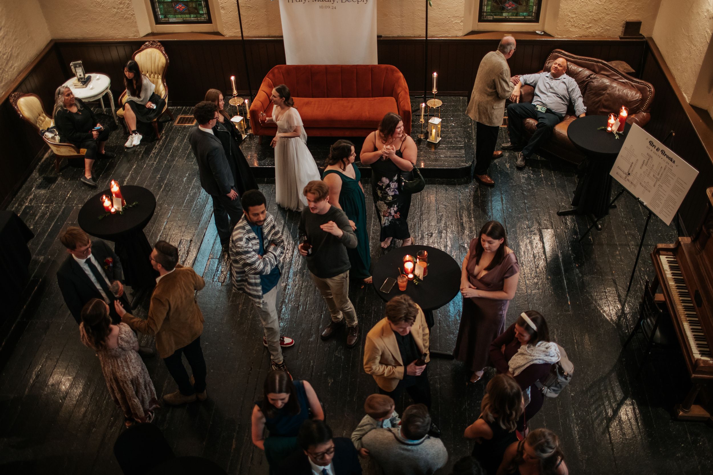 Aerial view of a crowded dance floor with people dancing and socializing at a dimly lit indoor venue.