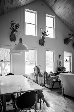 A modern dining room with mounted deer heads on white walls and large windows providing natural light.