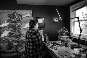 A series of black and white photographs showing an artist's workspace with sketches and drawing materials on a desk.
