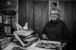 A series of black and white photographs showing someone working at a desk with papers and art materials.
