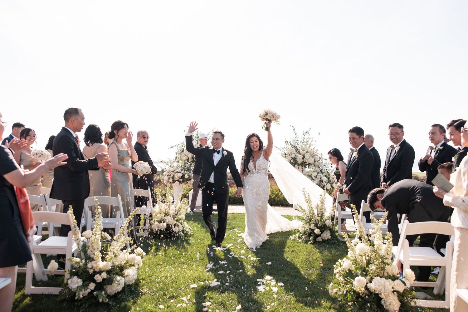 A wedding ceremony takes place in a rustic wooden barn with guests seated in rows and lanterns hanging above.