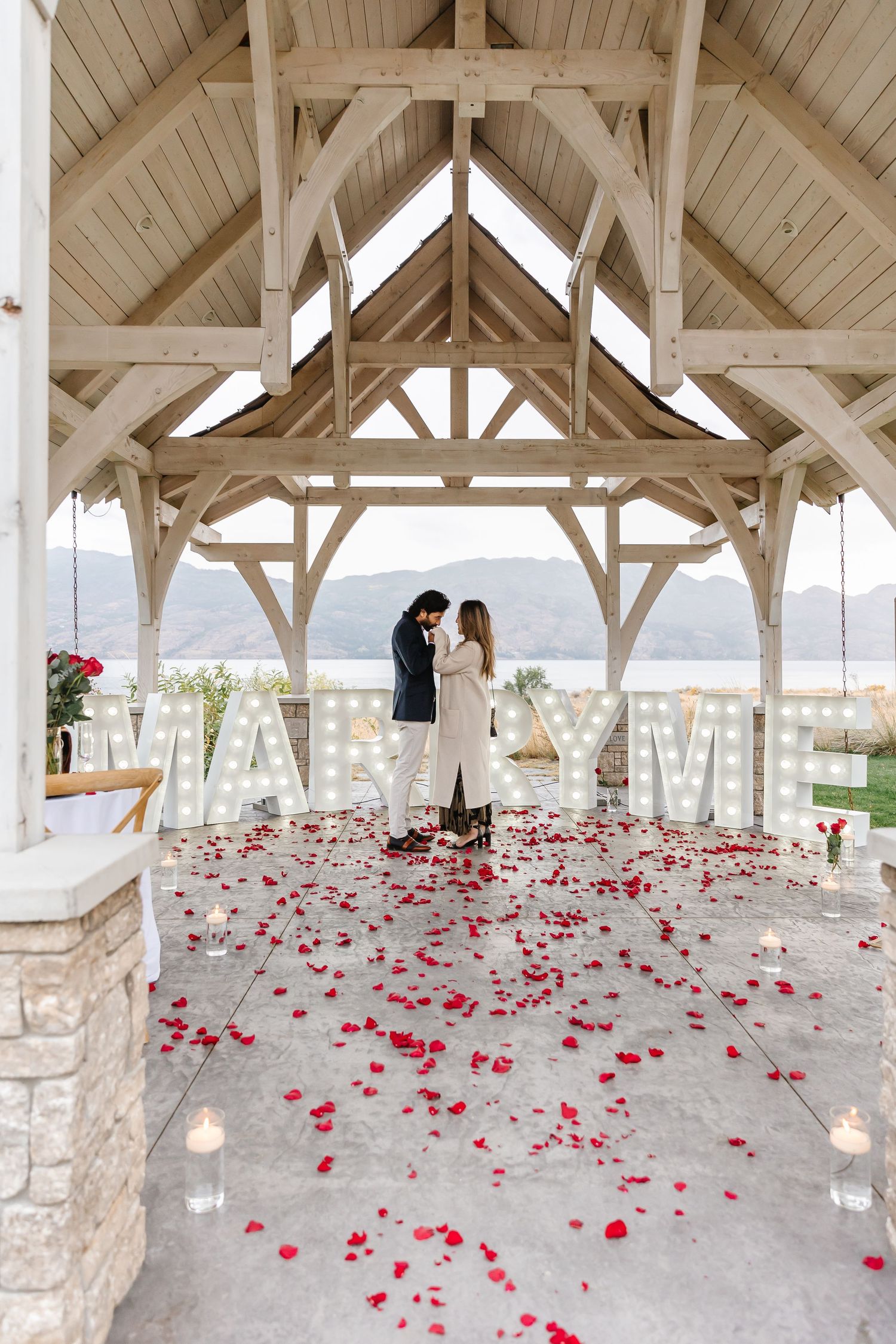 A romantic outdoor engagement with mountain view under a gazebo at Sanctuary Gardens in West Kelowna for surprise proposal photoshoot