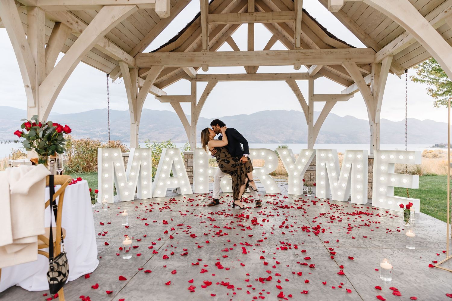 A romantic outdoor engagement with mountain view under a gazebo at Sanctuary Gardens in West Kelowna for surprise proposal photoshoot