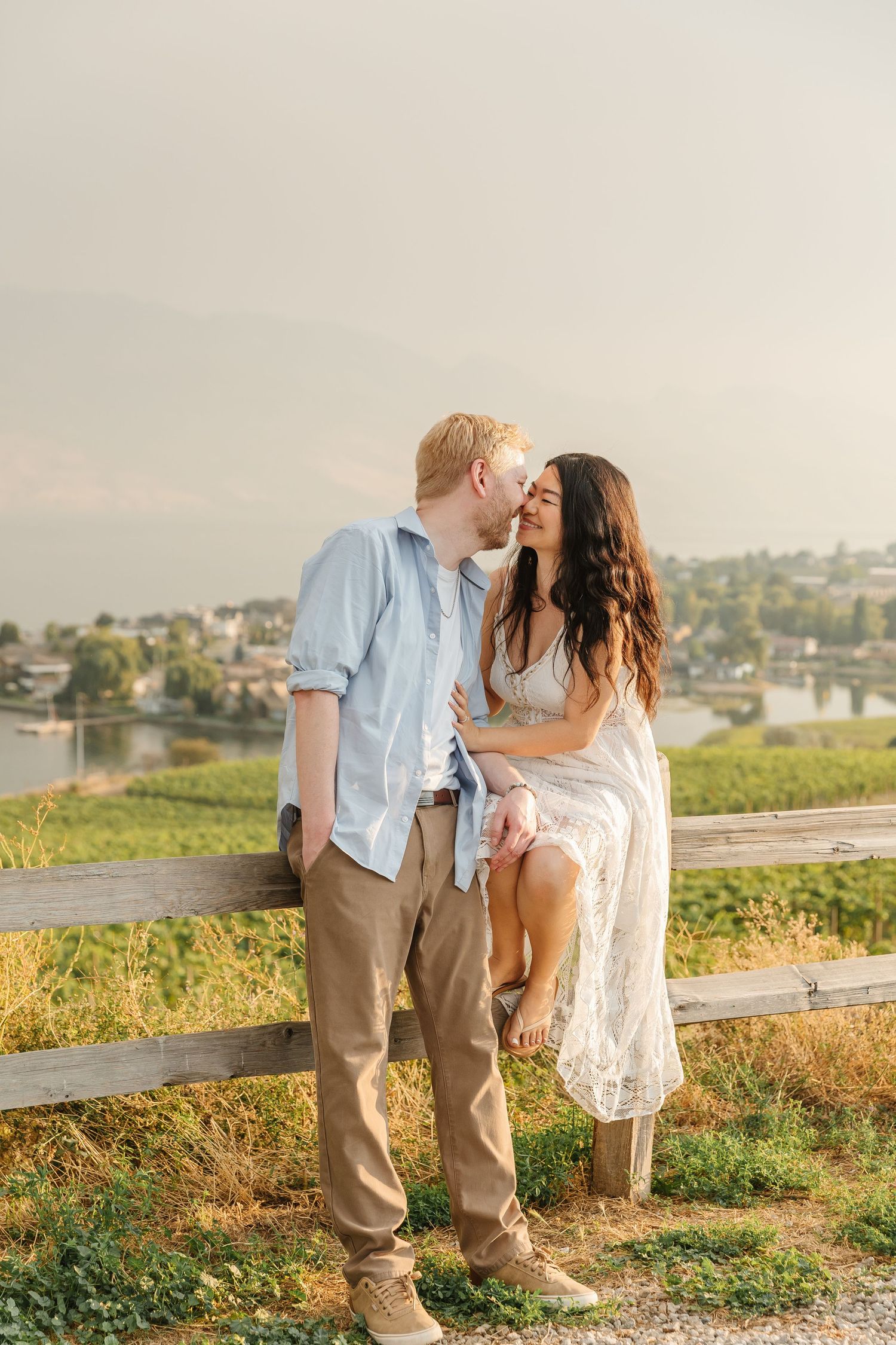 Romantic photos of a couple at sunset at Quails Gate Winery in West Kelowna, BC with a view of Okanagan Lake in the summer.