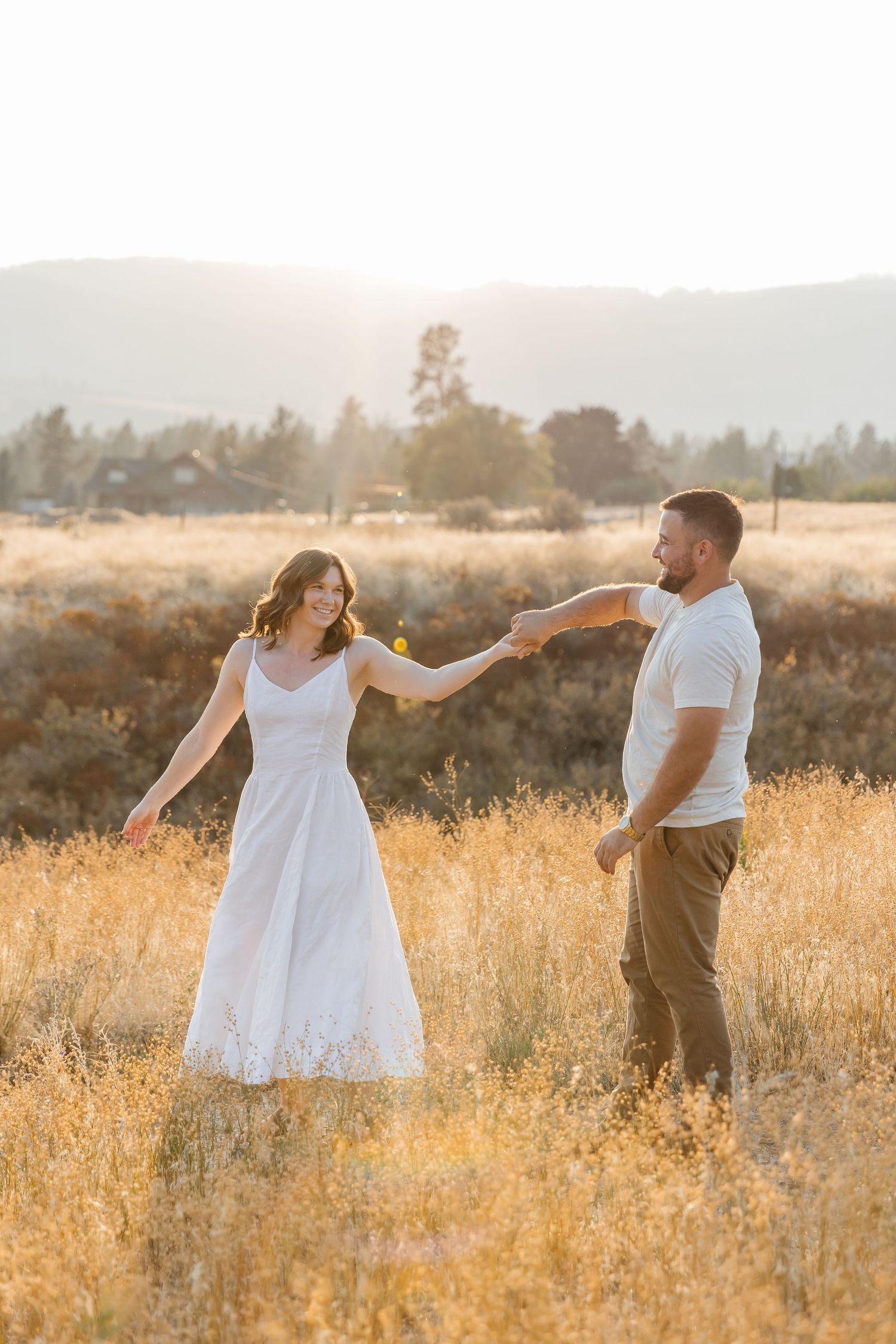 Engagement couple photo's in a golden wheat field at sunset in matching white and beige outfits in West Kelowna, BC at Sanctuary Gardens.