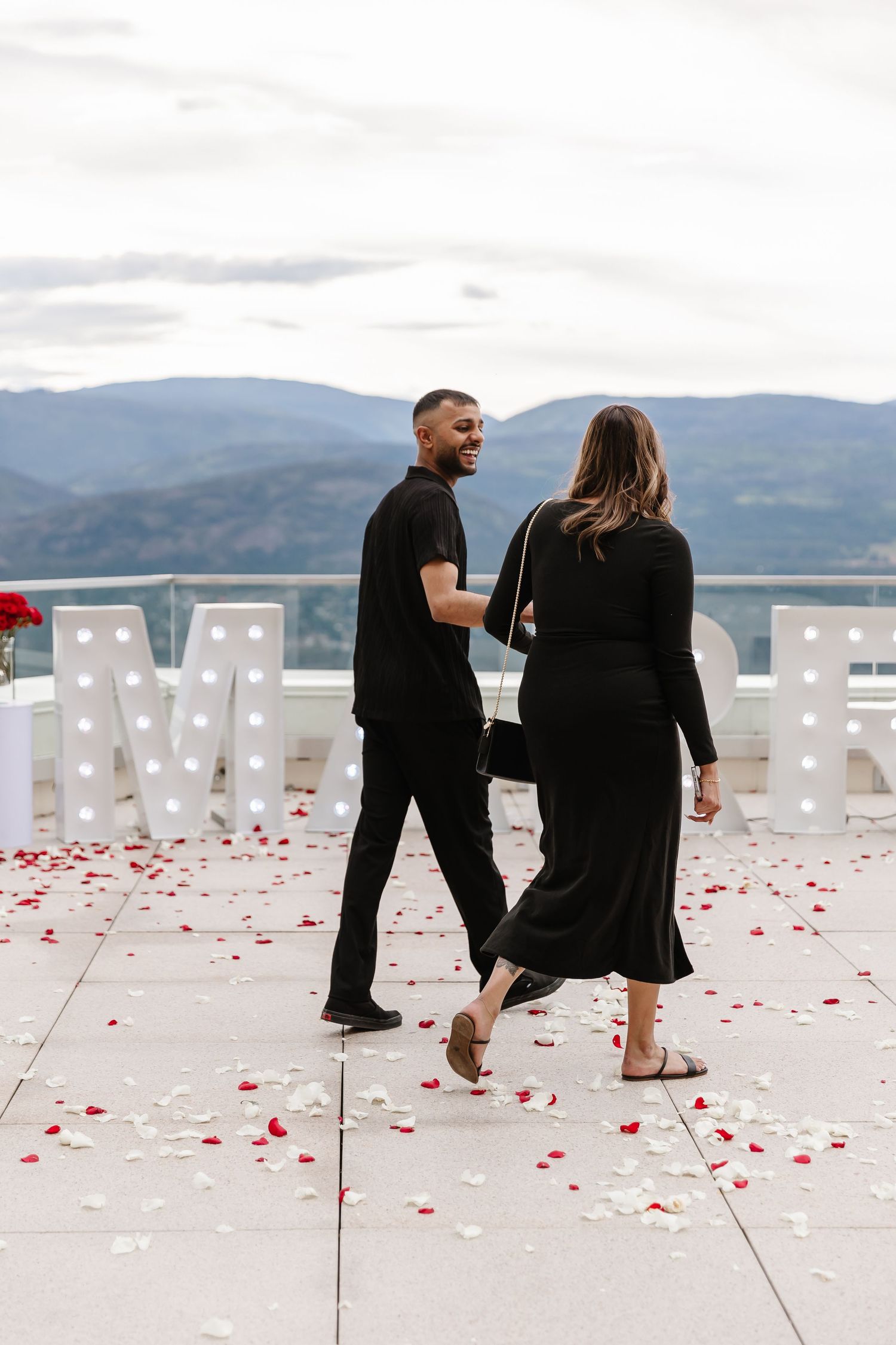 Surprise proposal photoshoot with rose pedals and marry me sign at sparkling hills resort in the Okanagan valley on a rooftop