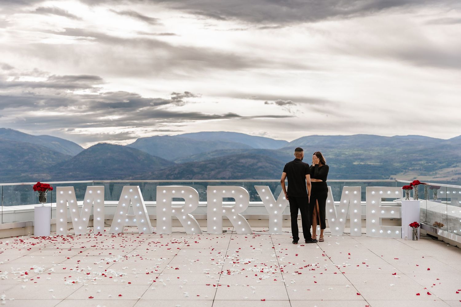 A romantic beach proposal setup with white letters spelling MARRY ME marquee sign arranged at sparkling hills in Kelowna bc for a photoshoot