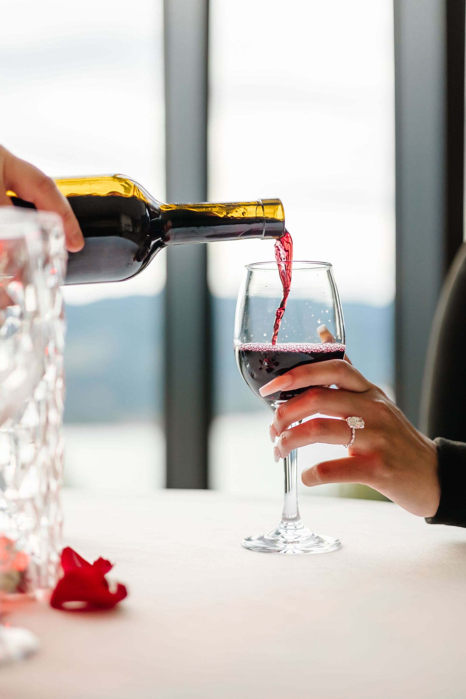 Red wine being poured into wine glasses on a white table in a bright setting at Sparkling Hills near Kelowna BC in Vernon for a photoshoot