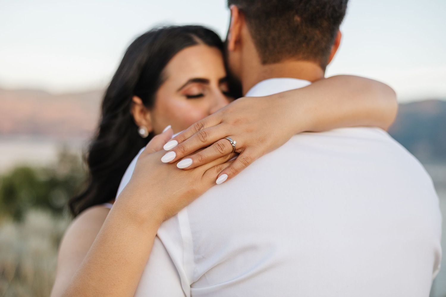 Romantic wedding couple embracing and kissing in an intimate moment outdoors at sunset for engagement photos in West Kelowna, BC