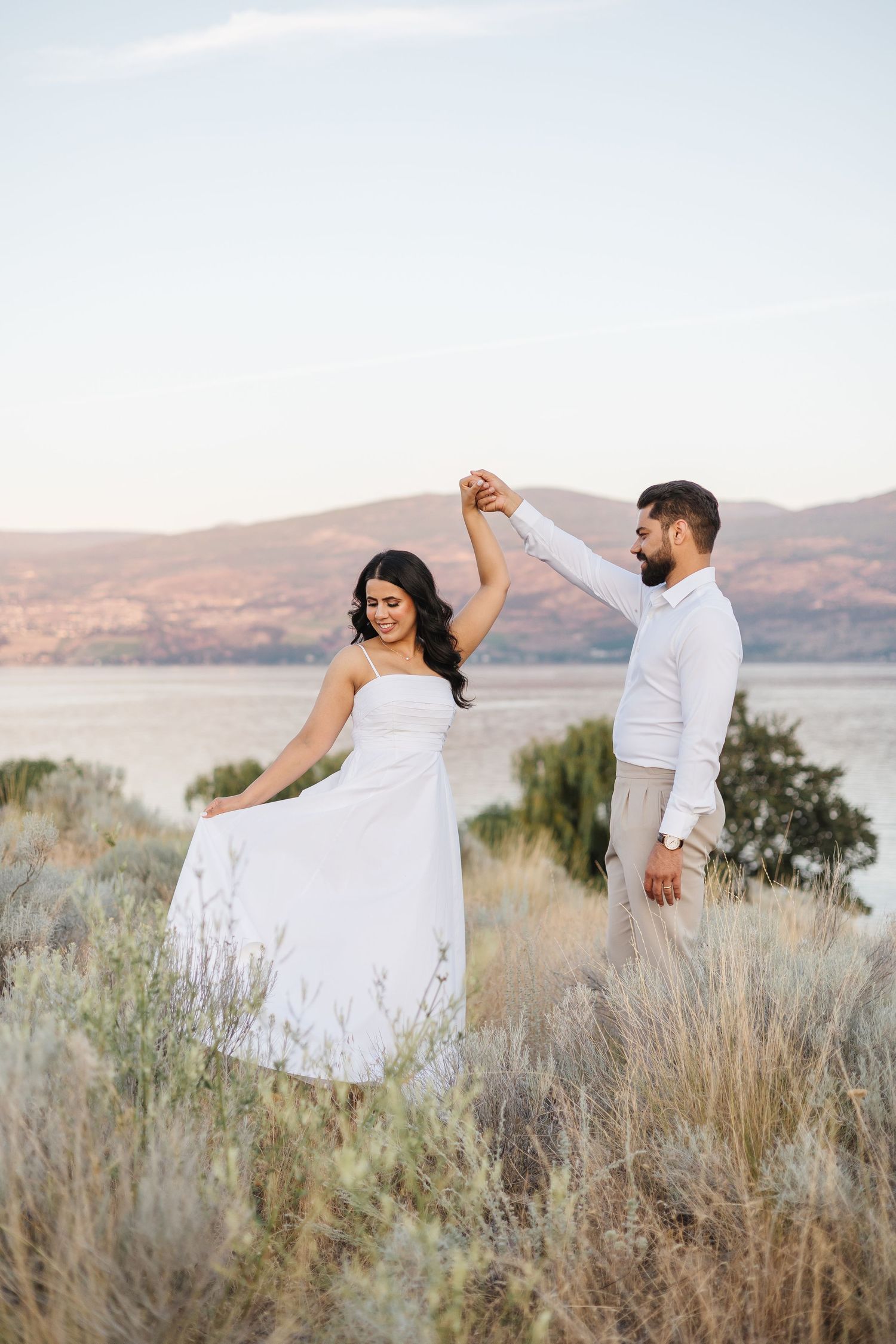 Couple's engagement photo's in a romantic pose against a scenic mountain landscape at sunset in West Kelowna, BC at Sanctuary Gardens