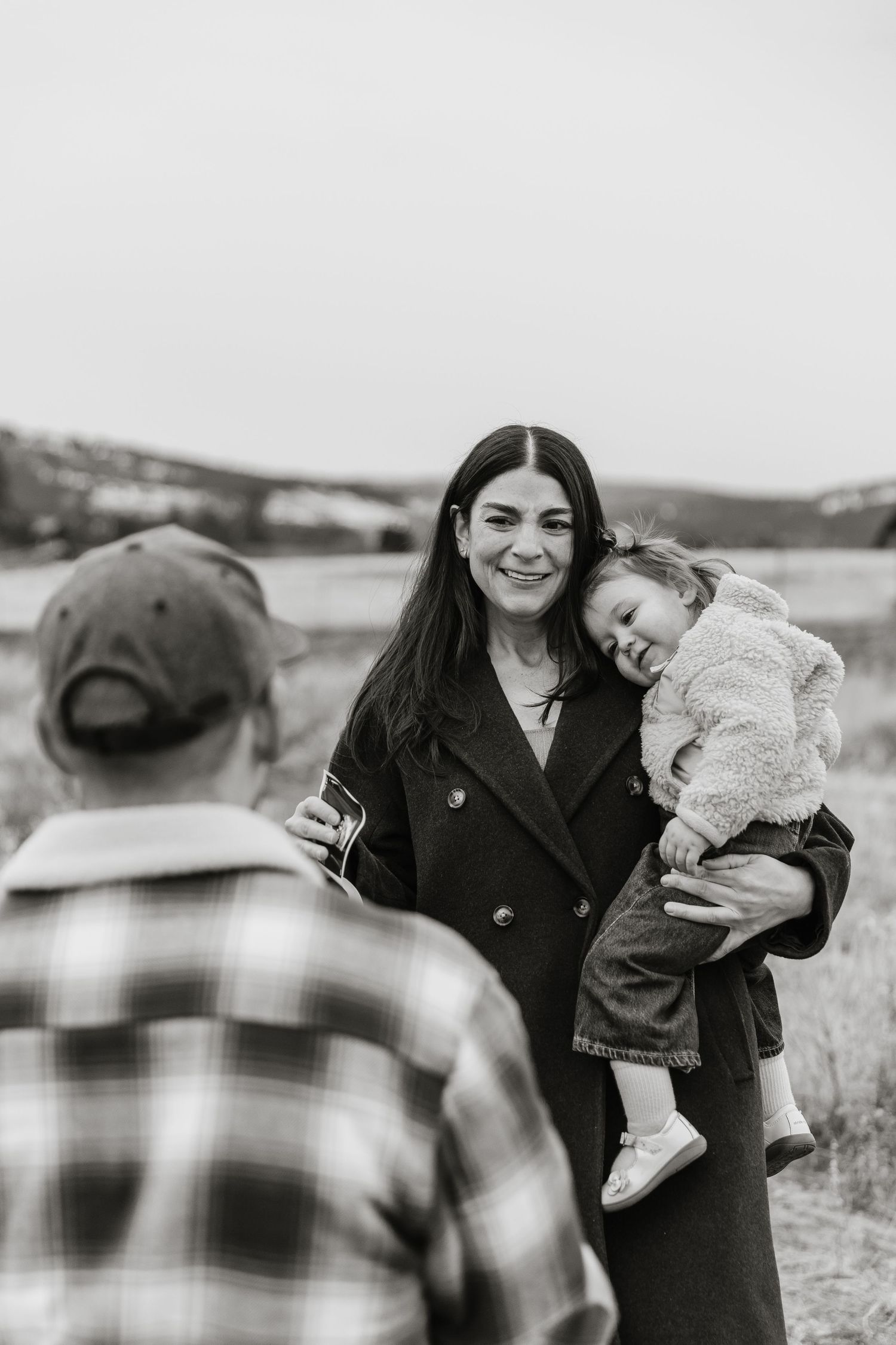 A candid black and white photo of surprise proposal in Kelowna, BC with family and baby announcement photos.