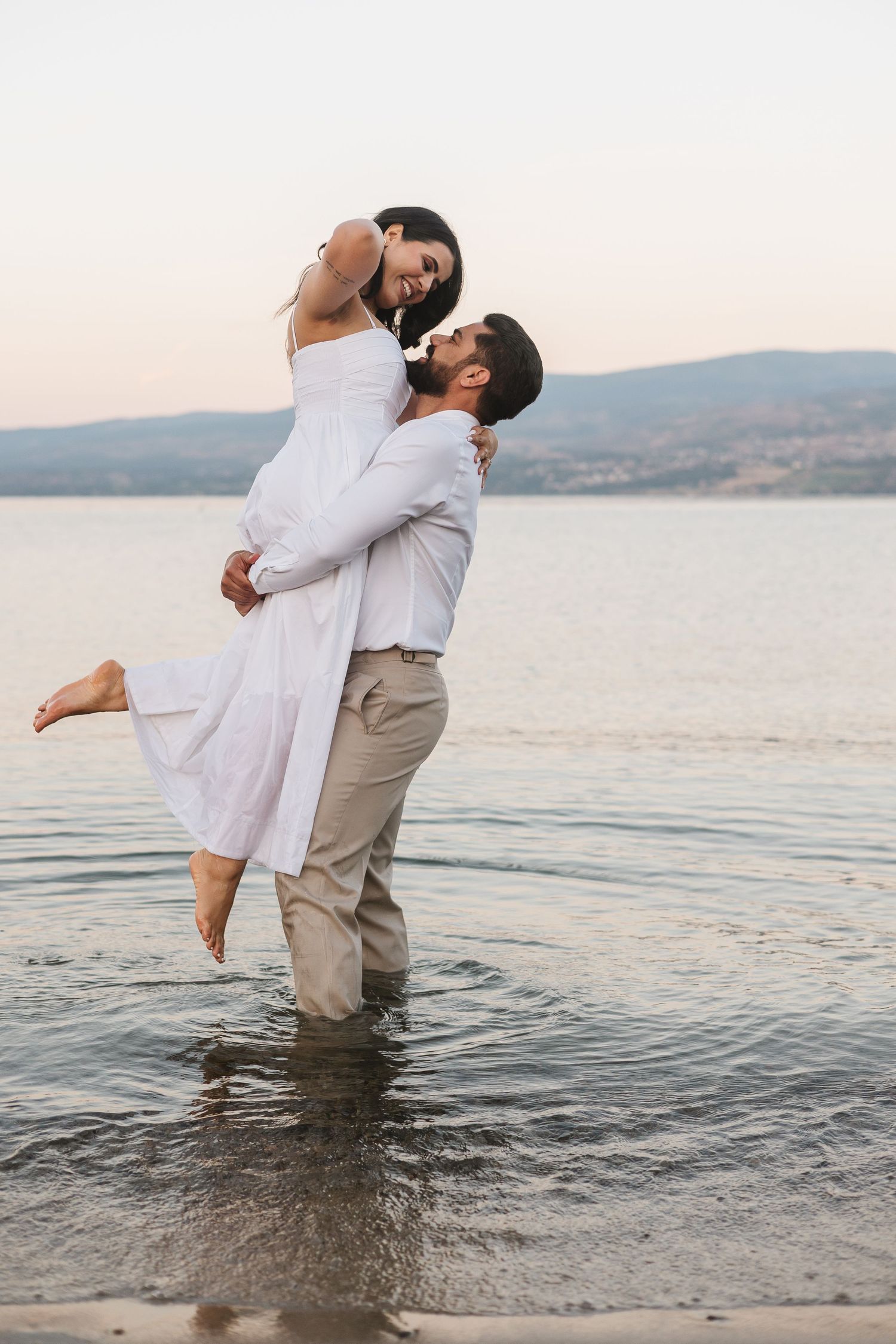 Couple photos in the lake in Kelowna, BC for an engagement session at sunset with a view of the lake and mountains.