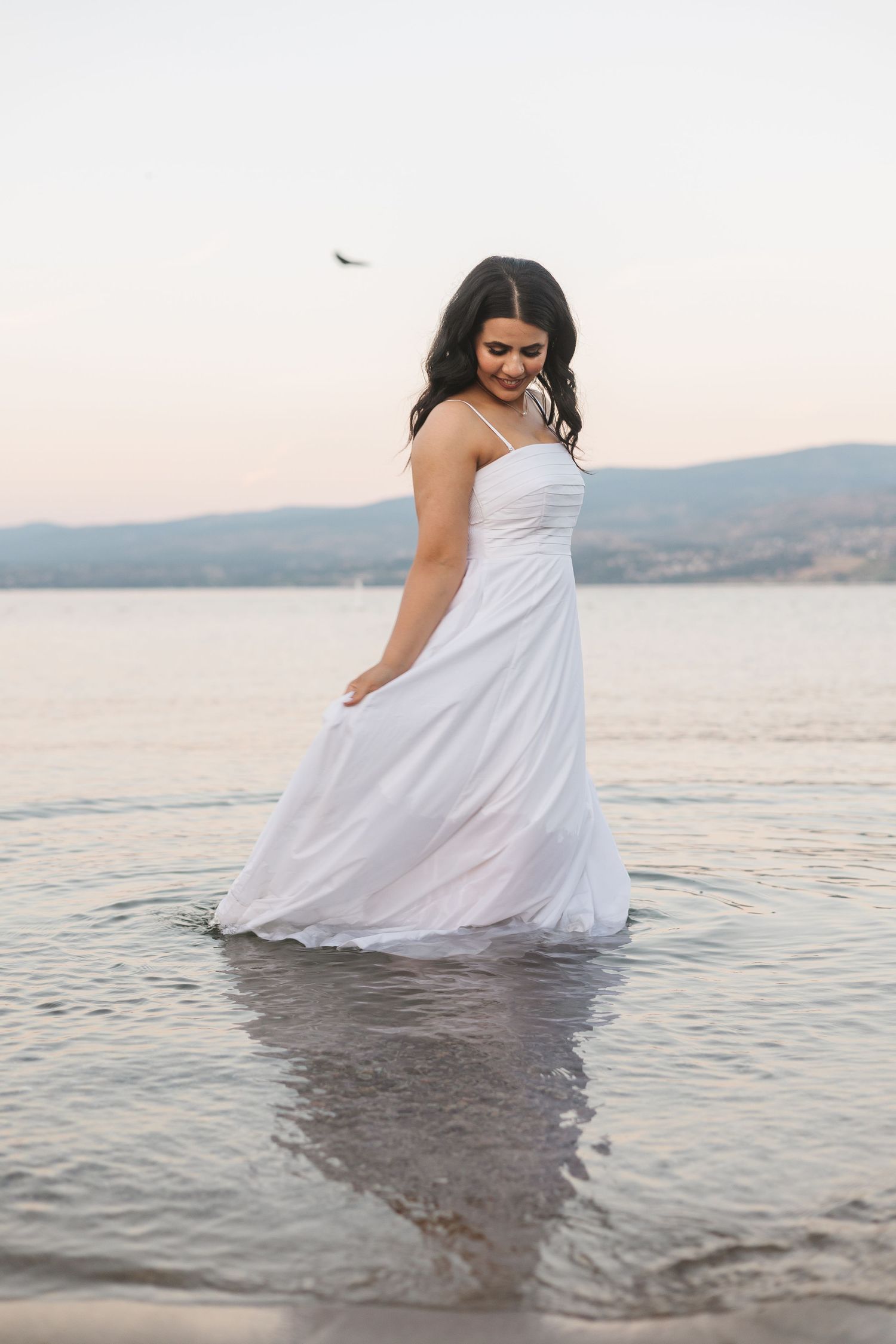 Solo shots in the water of Okanagan lake at sunset with mountains in the background for engagement photoshoot in West Kelowna, BC.