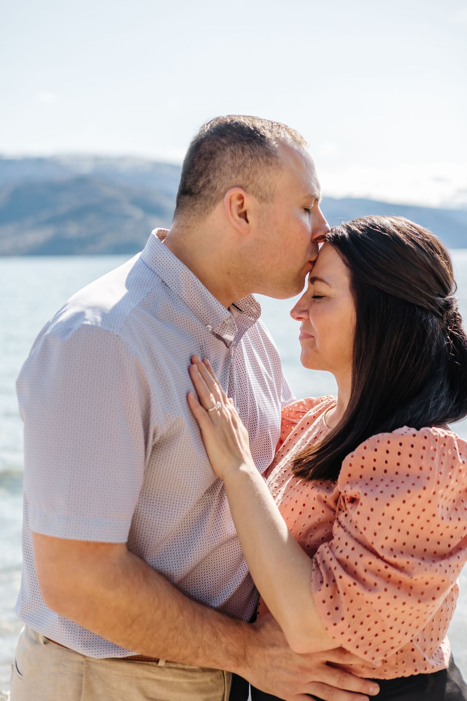 Couple sharing a kiss after a surprise proposal during an engagement session in Peachland, BC