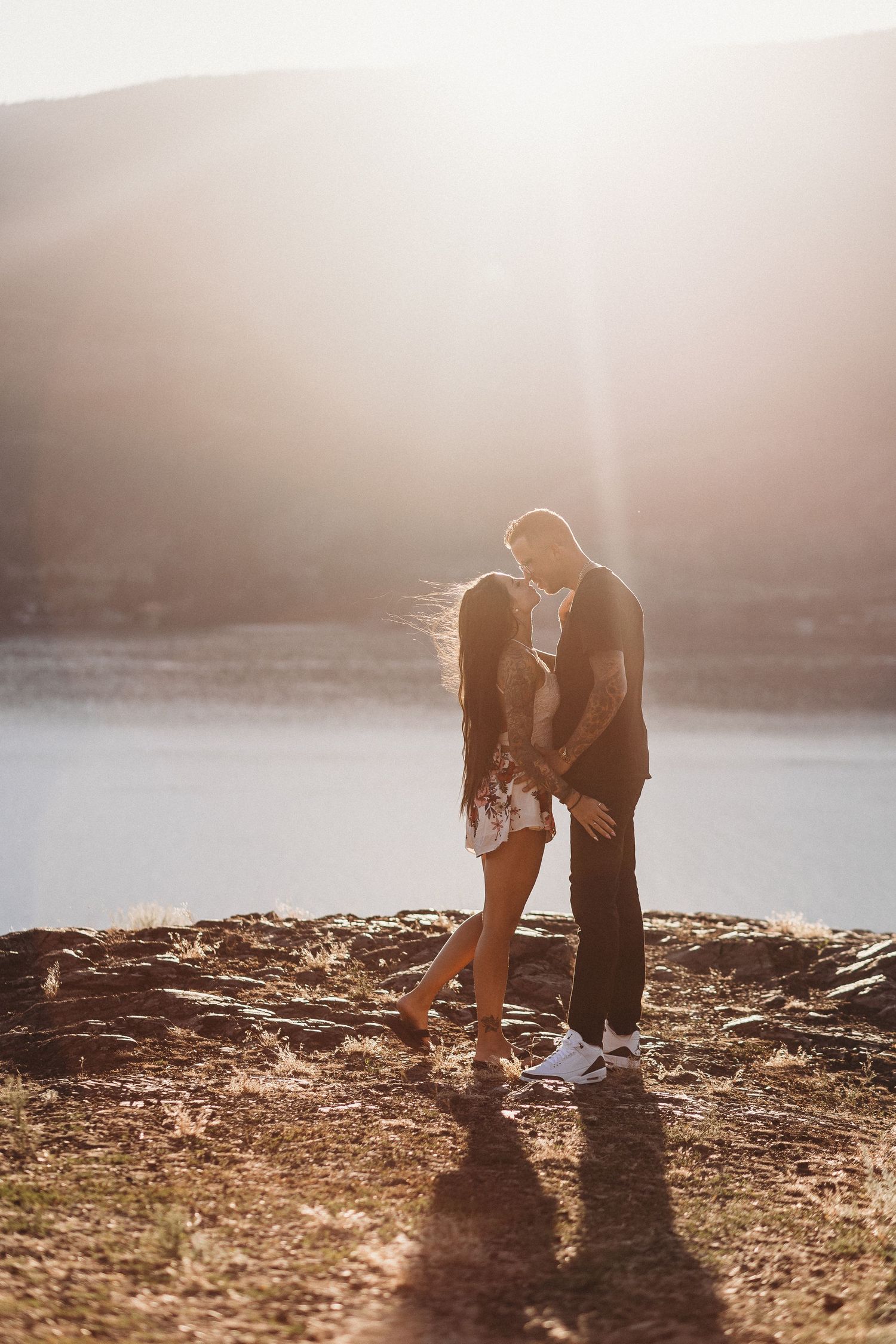Silhouettes of a couple share an intimate moment at sunset with a view of Okanagan lake in Kelowna for a couples photoshoot